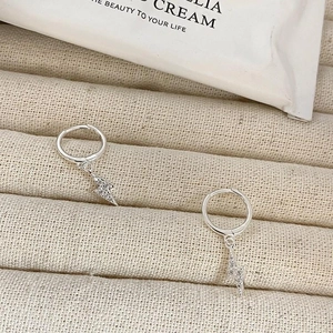 Macro shot of silver lightning hoop earrings with sparkling zircons on beige fabric