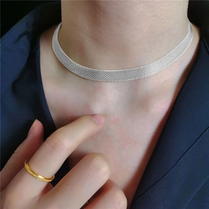 Detail shot of a silver mesh choker necklace and a minimalist gold ring on a model