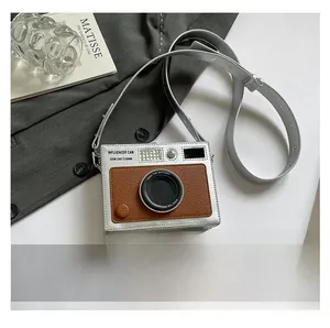 Mini vintage camera-shaped crossbody bag shown next to a smartphone for size reference