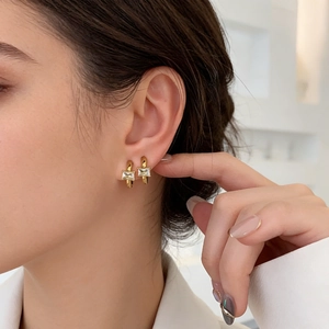 Close-up of 18k gold plated hoop earrings featuring a rectangular cubic zirconia stone