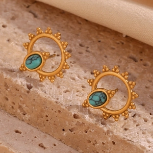 Detail of gold boho sun earrings with turquoise stones on natural stone base