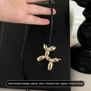 Detail of gold balloon dog pendant with mirror finish on long black cord necklace