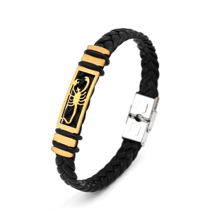 Macro detail of black braided leather bracelet with golden scorpion pattern metal plate