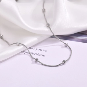 Macro shot of silver stainless steel snake chain necklace with spherical beads detail