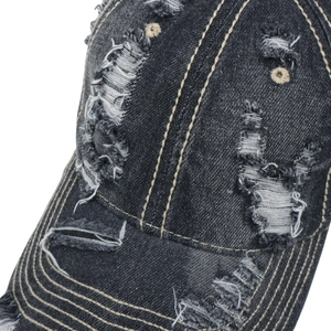 Detail of distressed dark denim baseball cap with vintage frayed holes and contrast stitching