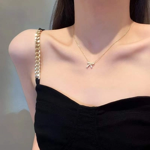Close-up of elegant gold bow pendant necklace with sparkling rhinestones on model neck