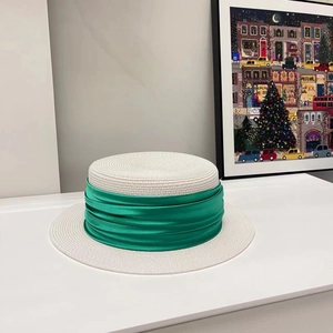 Detail of white flat top straw hat with wide green ribbon ribbon for summer vacation