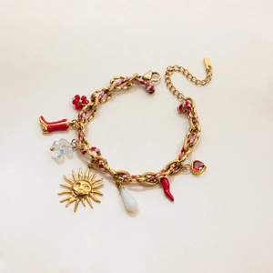 Dettaglio del bracciale a catena dorata con ciondoli rossi come cuore e sole