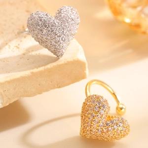 Macro shot of gold and silver heart-shaped ear cuffs with pavé-set shimmering zircons