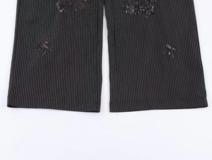 Detail of black pinstripe trousers featuring exquisite sequin flower embroidery on the hem