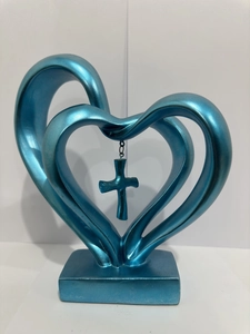 Detail shot of intertwined blue heart sculpture with a cross pendant on a stand