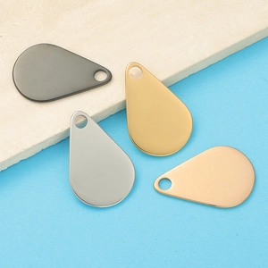Polished teardrop pendants in black, gold, silver, and rose gold on a stone base