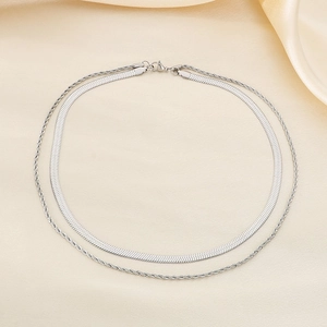 Detail of silver double-layered necklace with snake and twisted chains on silk fabric