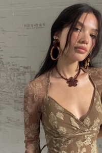 Detail of bamboo shaped earrings styled with a vintage brown floral long sleeve blouse