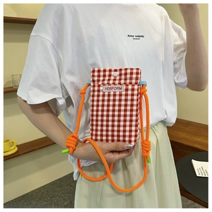 Detail of red checkered mini crossbody bag with orange rope strap and woven label