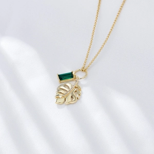 Macro detail of 925 silver necklace with emerald zircon and Monstera leaf pendant
