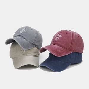 Detail of vintage washed baseball caps with sun embroidery in four classic colors