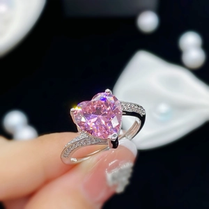 Anillo ajustable con circón de corazón rosa en acabado plateado sobre fondo negro elegante