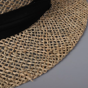 Close-up of natural straw weave texture and black ribbon trim on flat top sun hat
