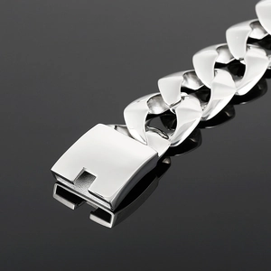 Close-up of a polished wide silver Cuban link bracelet on a dark reflective surface