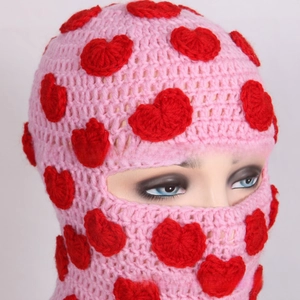 Detail of pink knitted balaclava mask with handmade red heart patches and eye opening