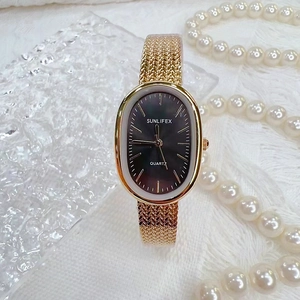 Elegant gold oval quartz watch with black dial and wheat mesh strap on white silk