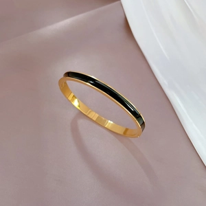 Macro view of gold plated stainless steel bracelet with black enamel inlay details