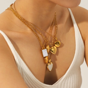 Layered gold necklaces with heart and shell pendants in polished stainless steel finish