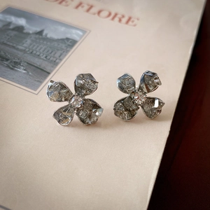 Detailed macro view of silver flower earrings with crystals on a magazine page background