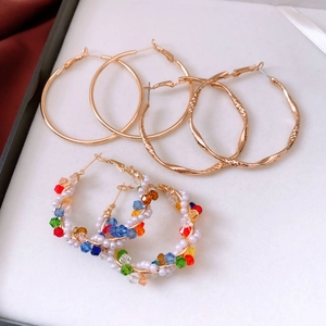 Detailed set of three golden earrings with smooth, twisted, and pearl beaded designs