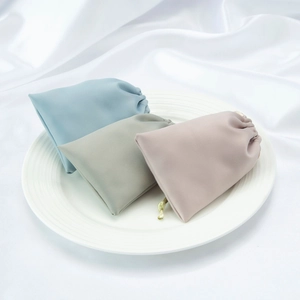 Macro detail of high-quality satin drawstring jewelry pouches in soft pastel colors