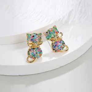 Macro shot of cat ear studs with colorful zircon stones and golden bow on white feathers