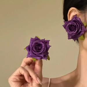 Detail of purple fabric rose earrings with simulation water droplets on silver needles.