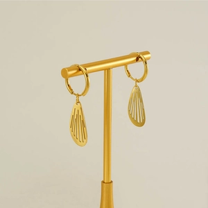 Detailed view of gold wing earrings with striped hollow design on a display stand