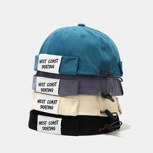 Detail showing four colors of cotton canvas brimless dockers caps with WEST COAST labels