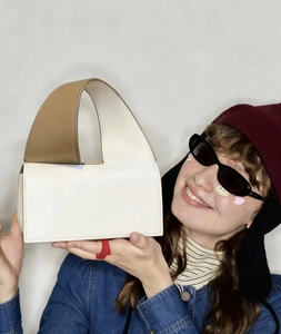 Close-up of stylish cream and tan color-block leather handbag with half-moon geometry