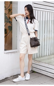Detailed view of checkered bucket bag with wide logo strap and stylish casual crossbody design