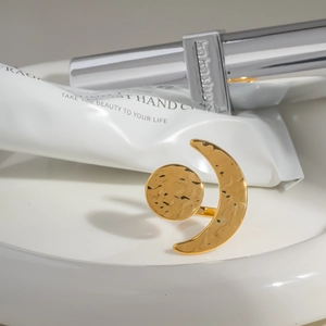 Detail of gold sun and moon open ring with hammer texture on white ceramic plate