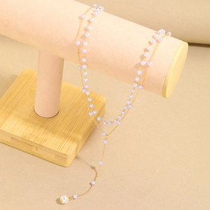Elegant gold Y-shaped layered necklace with white faux pearls on a display stand