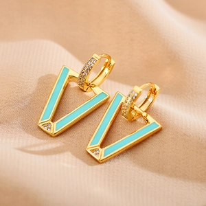 Macro shot of V-shaped gold earrings with green enamel inlay and sparkling white zircons