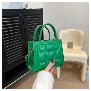 Détail d'un sac à main vert en cuir PU avec motif cœur gaufré et bandoulière amovible