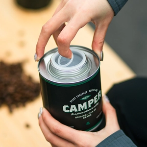 Sealed black tin coffee bean storage canister with airtight lid and Camper label