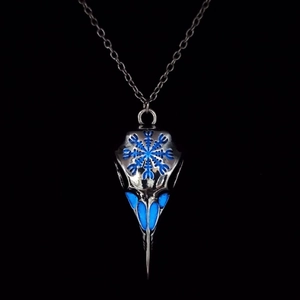 Macro shot of Viking bird skull necklace with glowing blue runes on dark background