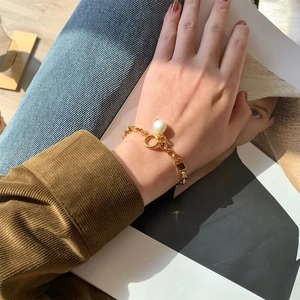 Détail d'un bracelet chaîne plaqué or 18 carats avec perle et fermoir à bascule OT au poignet