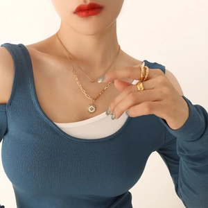 Zweilagige Goldkette mit Bienenanhänger und strukturierte Ringe an einem Model