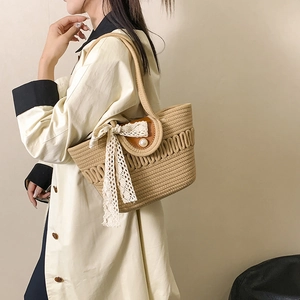 Straw woven tote bag with lace bow and pearl clasp shown on model shoulder