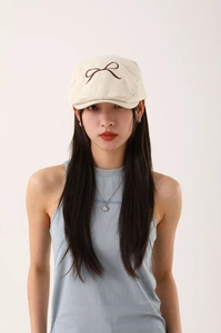 Détail du béret beige clair avec broderie nœud marron foncé et texture en coton structuré