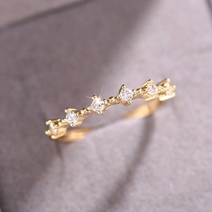 Elegante anillo apilable de oro con cristales redondos brillantes sobre una banda con ondas