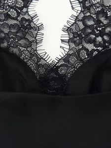 Detailed close-up of eyelash lace trim and satin fabric on a black camisole top
