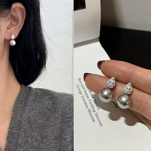 Detail of teardrop CZ stone and grey pearl earrings on model and in a close-up view